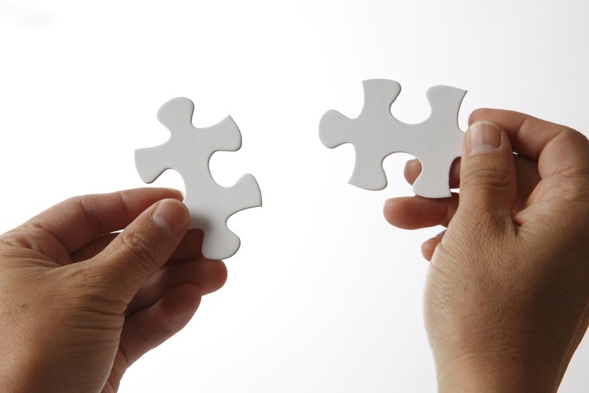 Zwei H&auml;nde, die zwei Puzzleteile zusammenf&uuml;gen, als Symbol f&uuml;r passgenaue Compliance-L&ouml;sungen